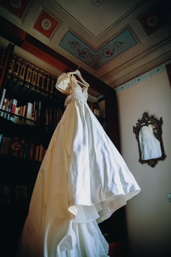 Abito da sposa appeso in una stanza con la libreria