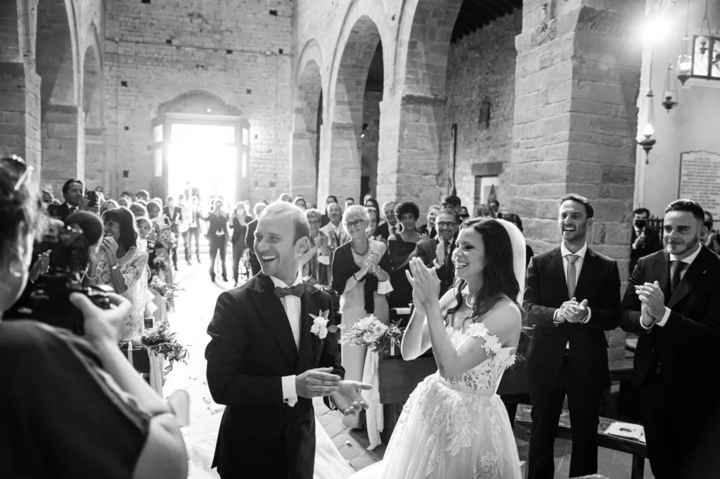 Invitati che applaudono gli sposi in chiesa, in bianco e nero