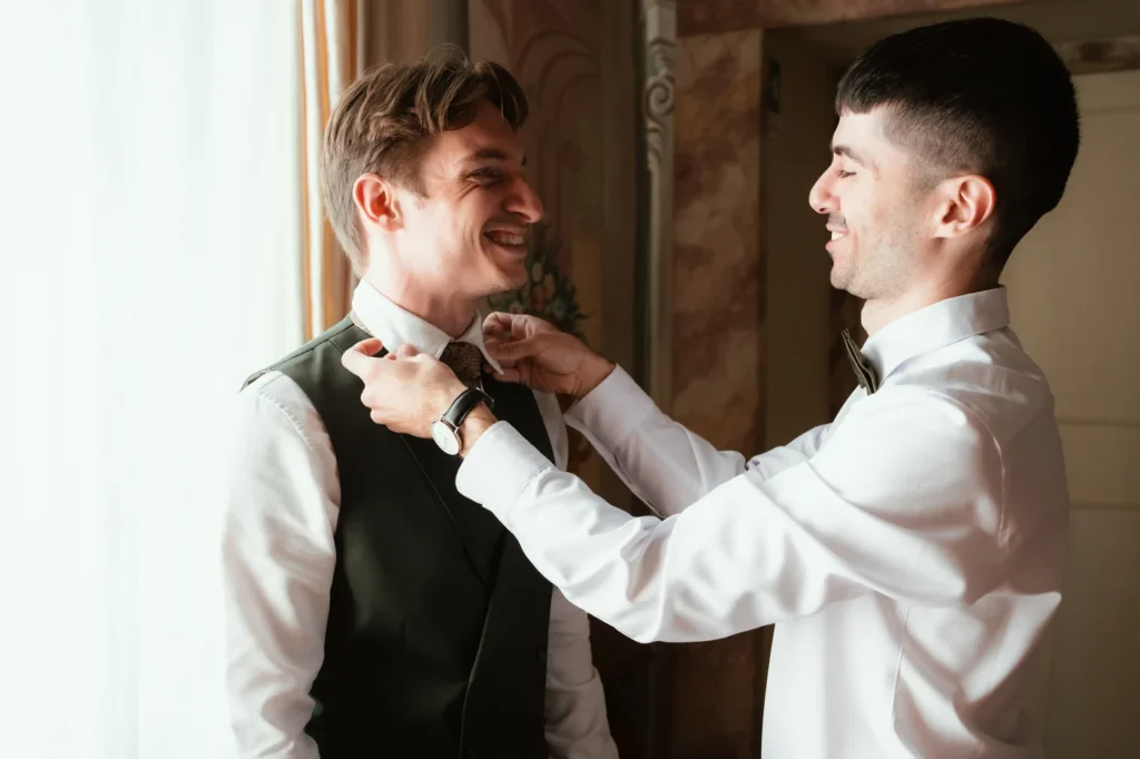 Lo sposo sorride mentre un amico gli sistema la cravatta