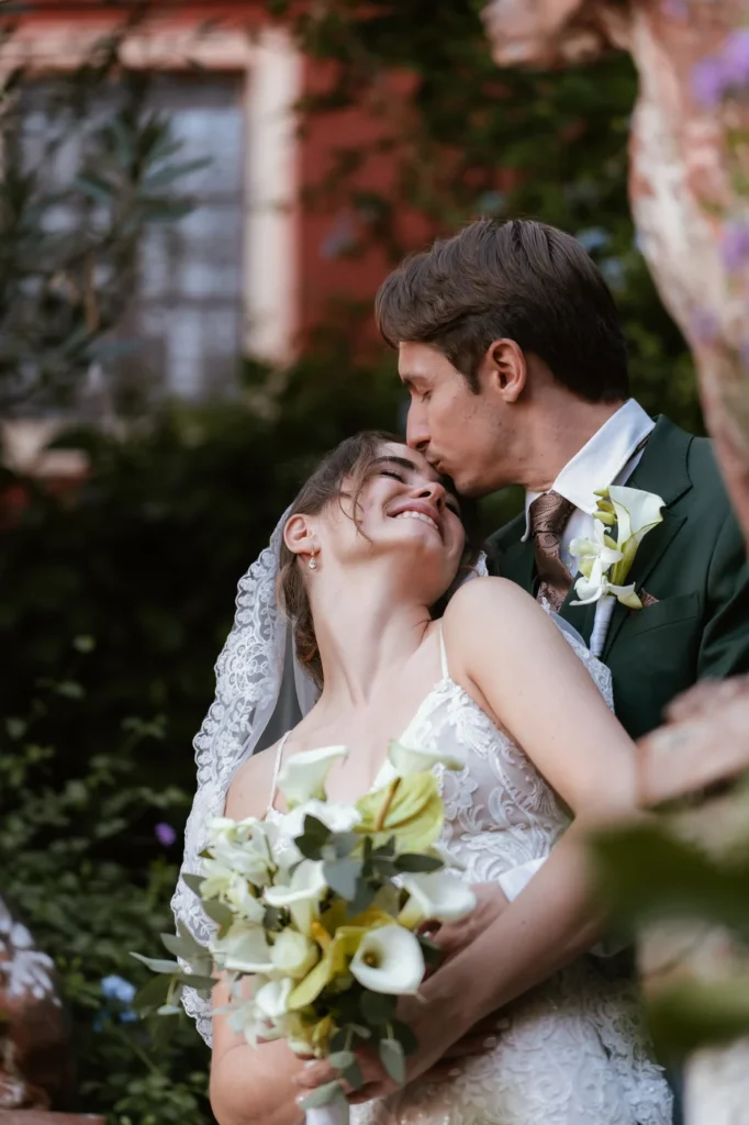 Lo sposo bacia la sposa sulla fronte nel giardino