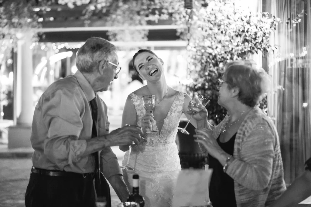 Sposa che brinda ridendo con gli invitati, in bianco e nero