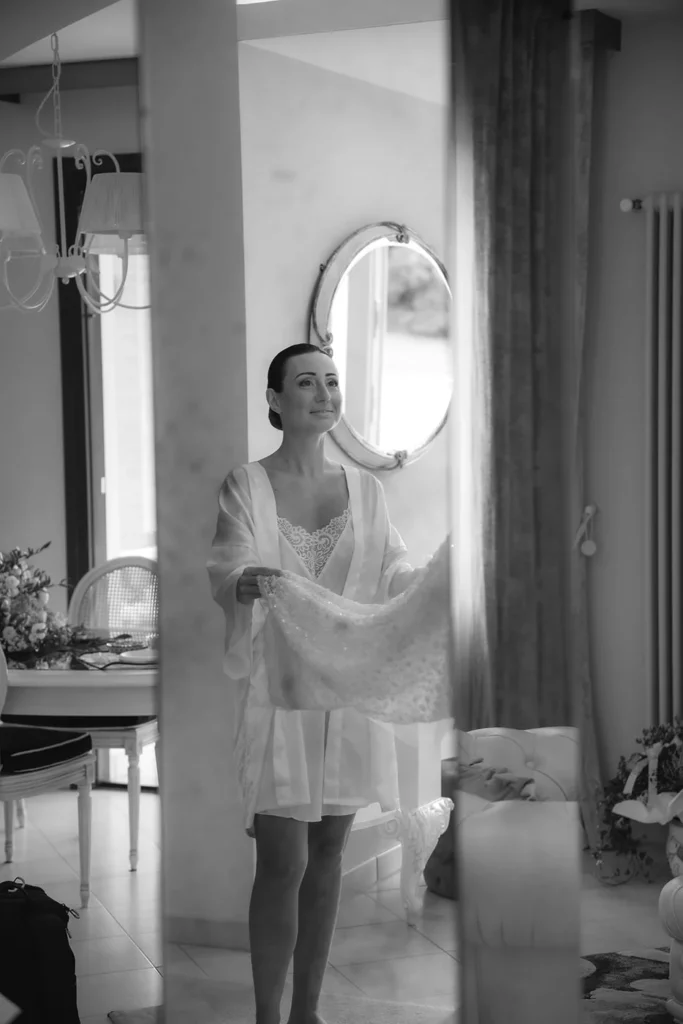La sposa in vestaglia accanto all'abito, in bianco e nero