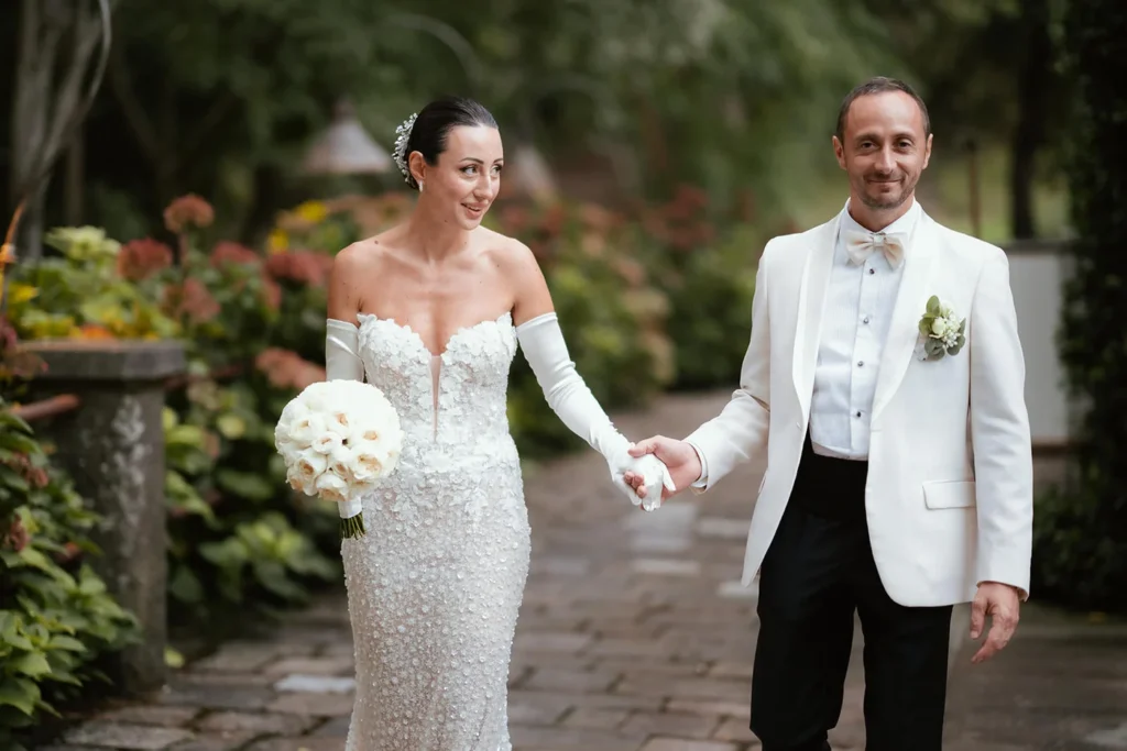Gli sposi mano nella mano nel giardino della villa