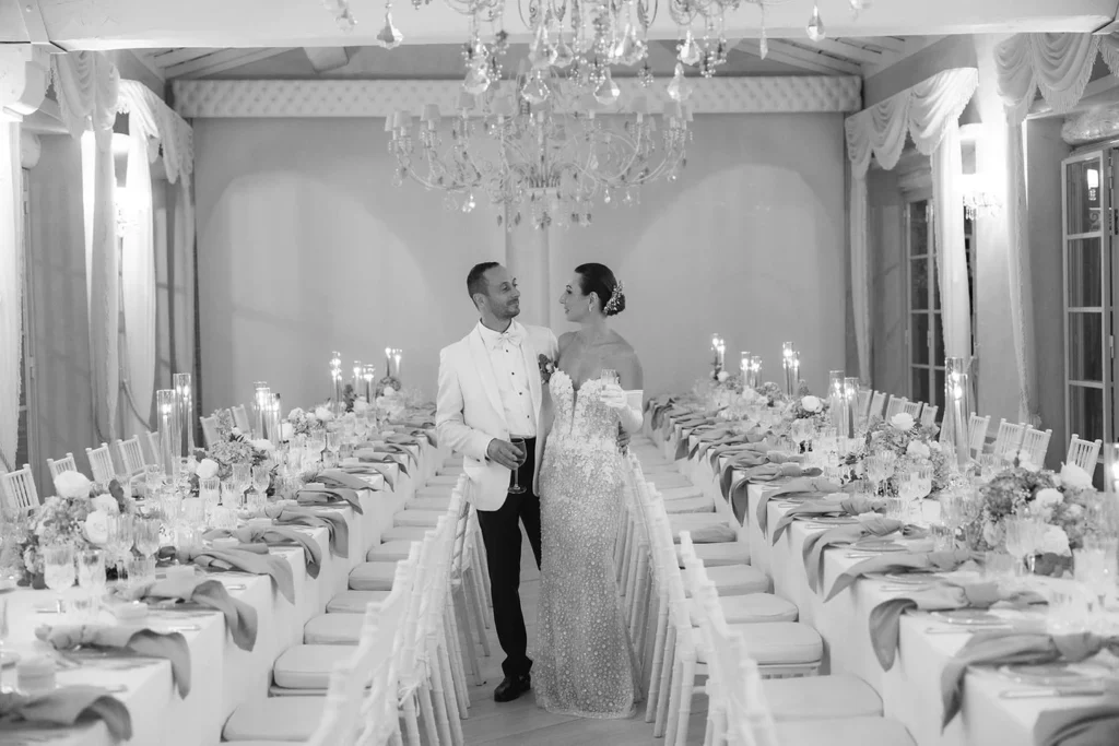 Gli sposi tra i tavoli della sala, in bianco e nero