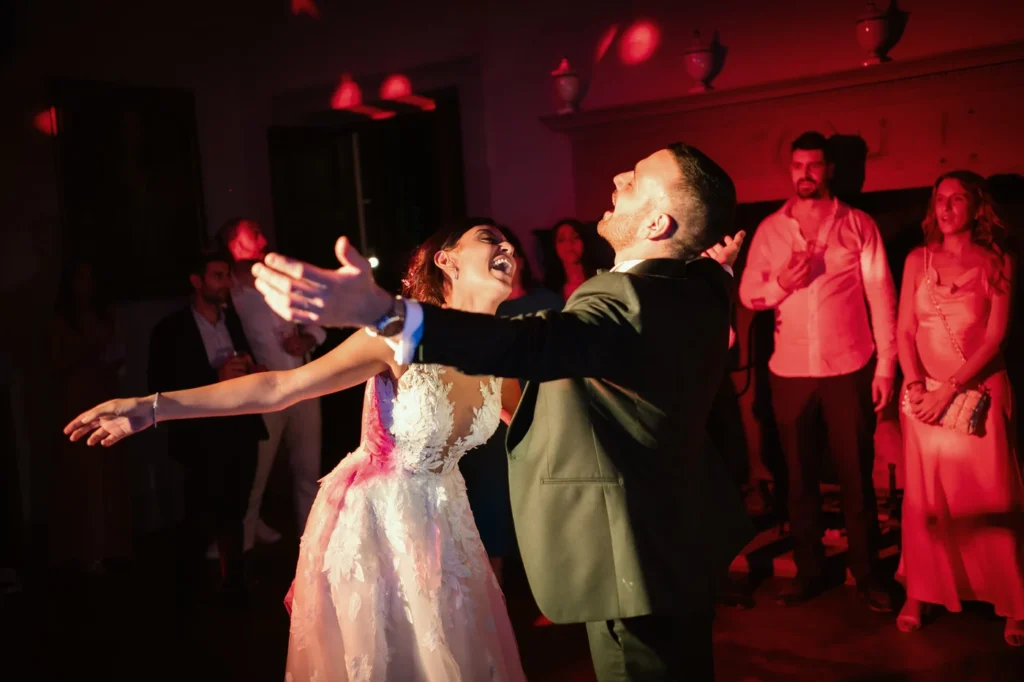 Sposi che ballano con gli invitati tra luci rosse