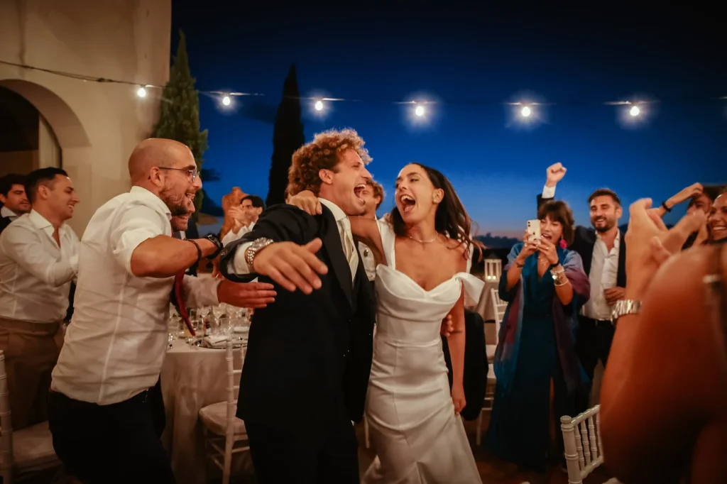 Sposi che festeggiano con gli invitati sotto le luci della sera