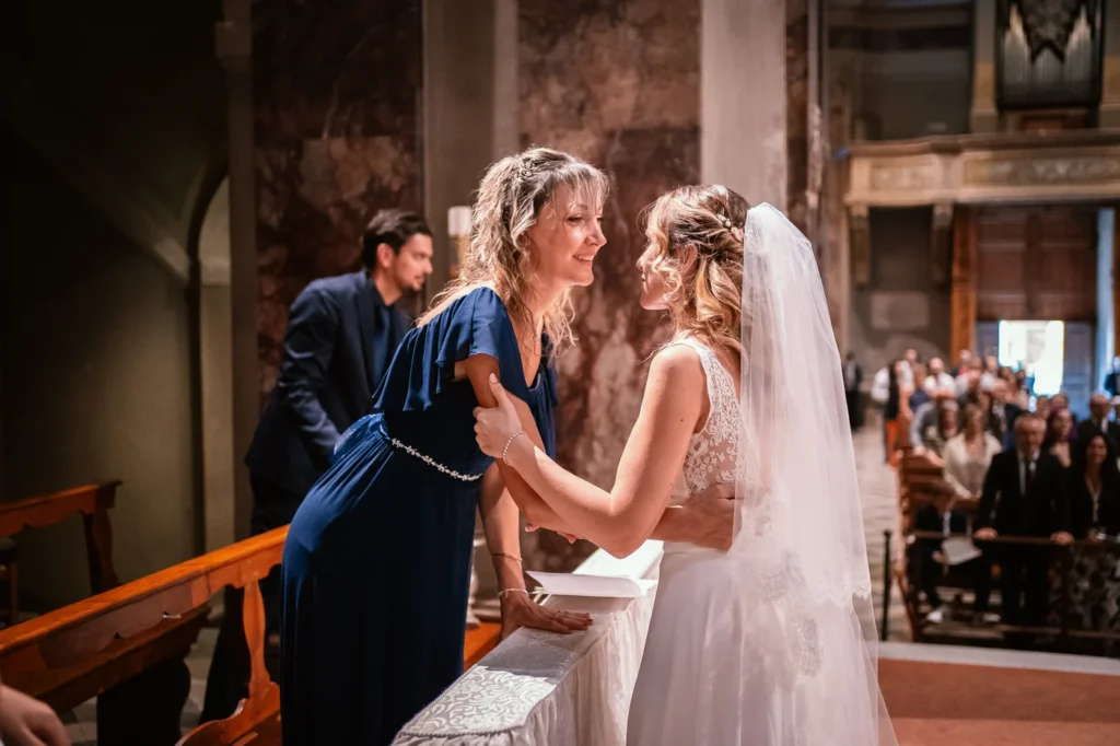 La sposa abbraccia un'invitata tra i banchi