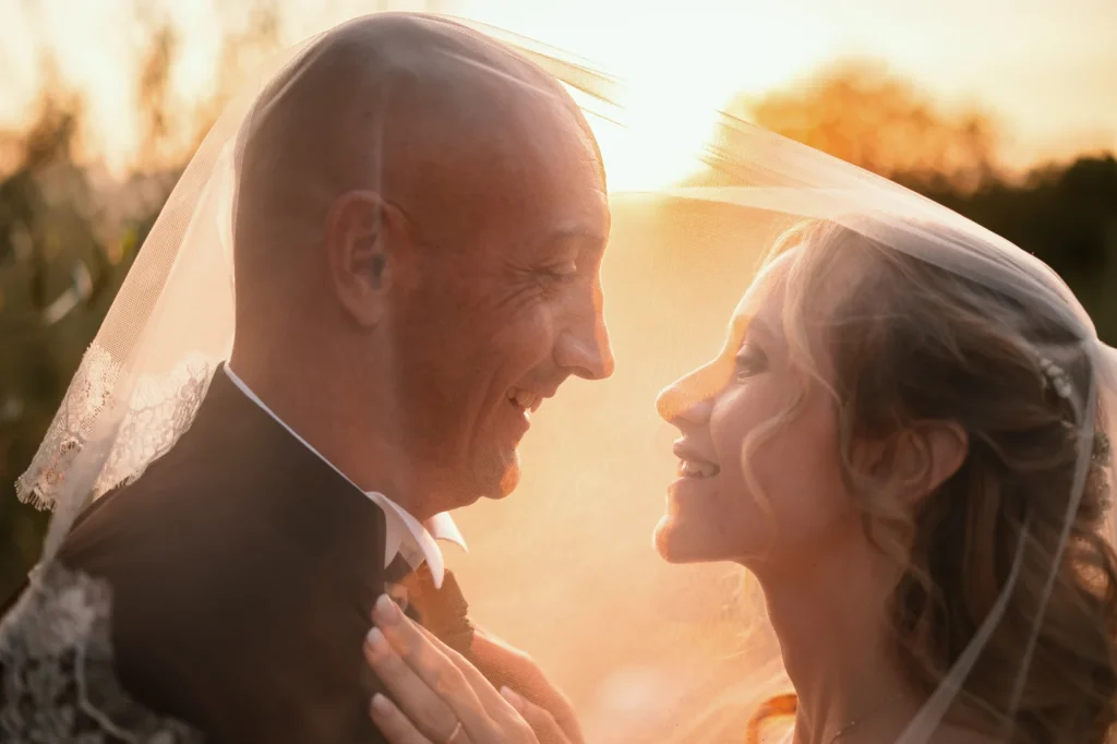 Gli sposi sorridono sotto il velo al tramonto