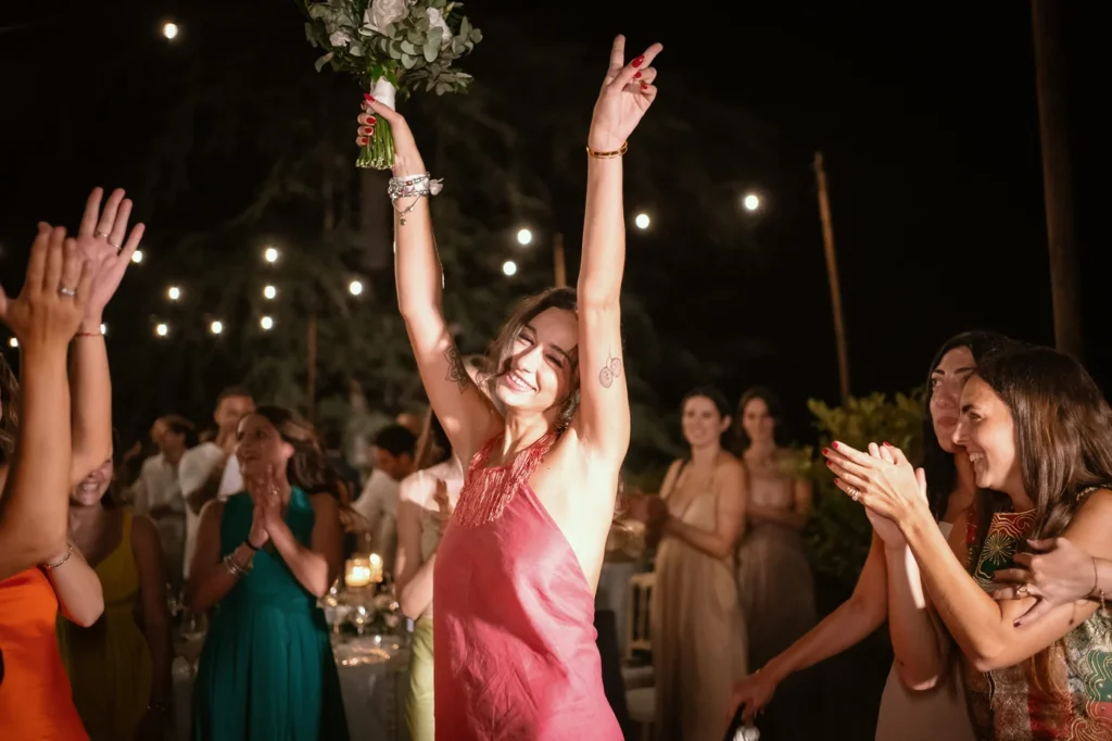 Invitata che esulta alzando il bouquet durante la festa
