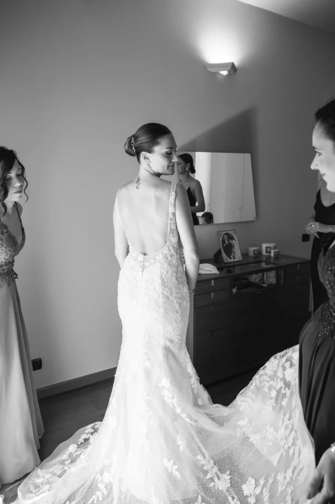 Sposa mentre le sistemano lo strascico dell'abito, in bianco e nero