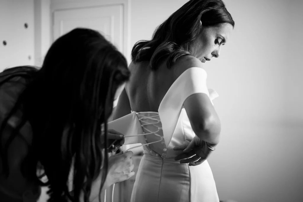 Sposa mentre le allacciano l'abito, in bianco e nero