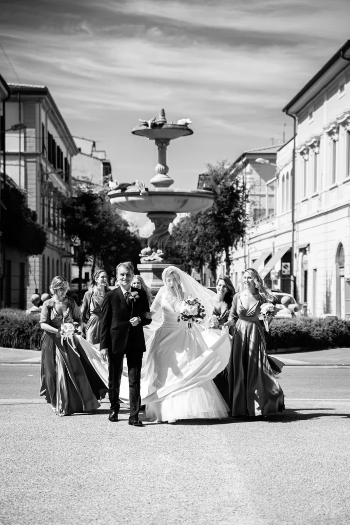 Sposa e damigelle in una piazza con fontana, in bianco e nero