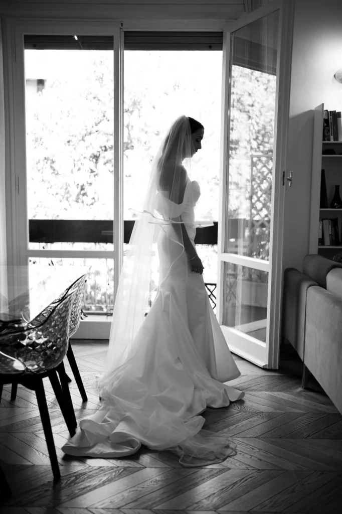 Sposa accanto alla finestra prima della cerimonia, in bianco e nero