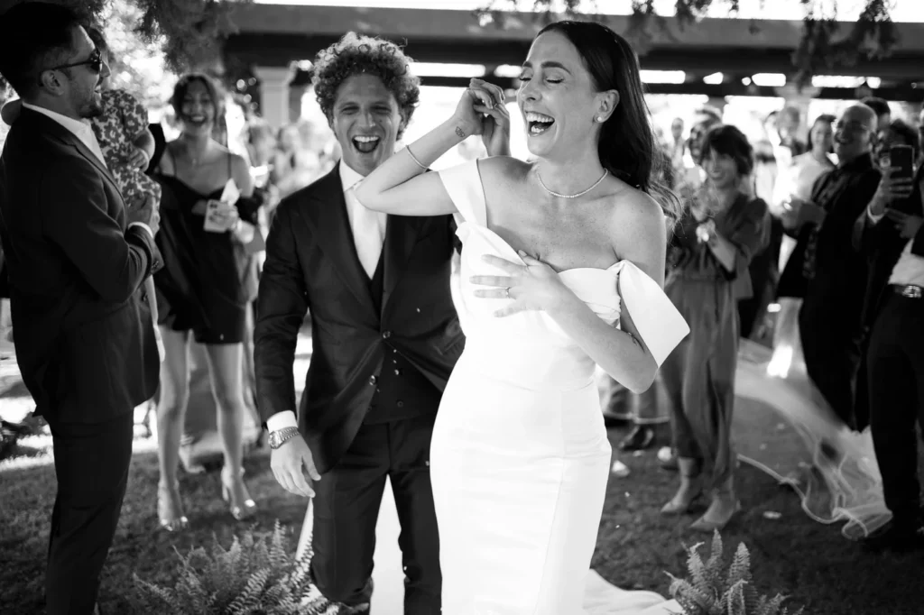 Sposi che ridono tra gli invitati, in bianco e nero
