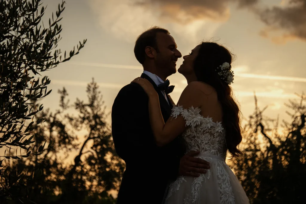 Silhouette degli sposi al tramonto tra i rami di ulivo