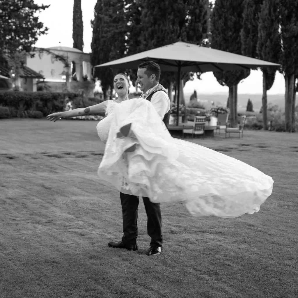 Sposo che solleva la sposa sul prato, in bianco e nero