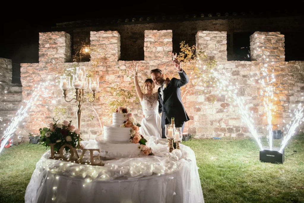 Sposi al taglio della torta tra le fontane di luce davanti alle mura