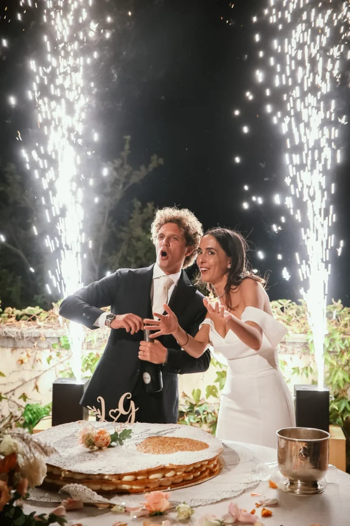 Sposi che ridono al taglio della torta tra le fontane di luce