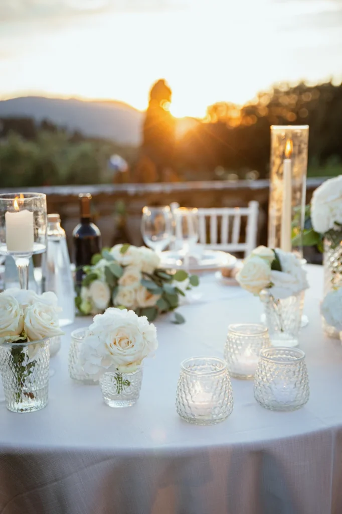 Tavola del ricevimento con candele e fiori al tramonto